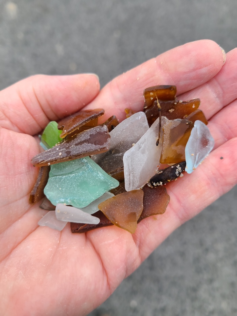 A hand holding a collection of beachglass.